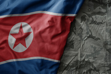 waving flag of north korea on the old khaki texture background. military concept.