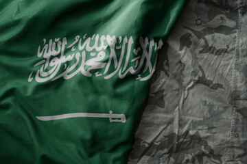 waving flag of saudi arabia on the old khaki texture background. military concept.