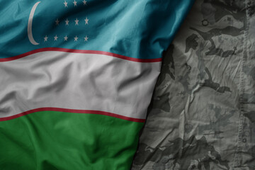 waving flag of uzbekistan on the old khaki texture background. military concept.