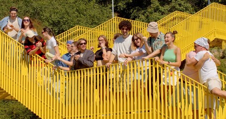 Celebrating special occasion, achievement, or simply having fun. Students lifestyle. Yellow outdoor staircase, sunny weather Group of young people clapping hands, expressing happiness joy excitement.