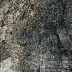 Weathered seaside rock face texture. Aged volcanic stone wall surface background pattern with cracks and scratches. Ischia Island, Italy.