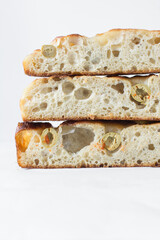 homemade olive focaccia on a white background, Flatlay of focaccia with green olive topping, fresh homemade focaccia bread