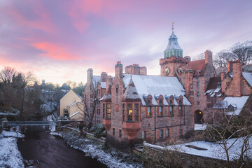 Quaint and historic Dean Village covered in snow along the Water of Leith during a winter sunset in...