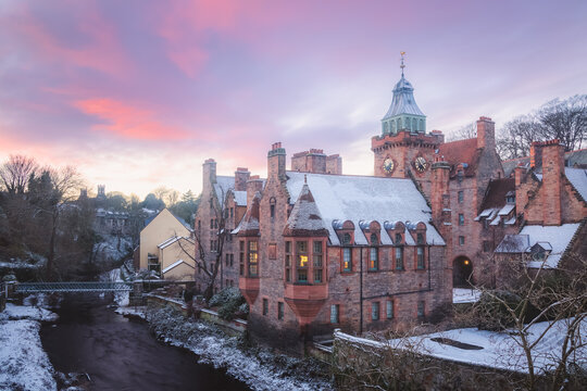 Quaint and historic Dean Village covered in snow along the Water of Leith during a winter sunset in Edinburgh, Scotland.