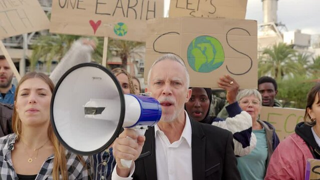 Group of activists protesting with placards fighting for climate change in front of a polluting factory. Environmental conservation and global warming concept.