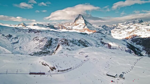 Aerial view of Zermatt Matterhorn and Gornergrat Railway during winter in Switzerland. View from above of a train transporting tourists and people skiing The Alpine mountain.