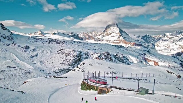 Aerial view of Zermatt Matterhorn and Gornergrat Railway during winter in Switzerland. View from above of a train transporting tourists and people skiing The Alpine mountain.