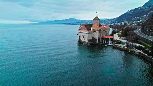 Drone view of Lakeside Chillon Castle with red rooftop in Switzerland. Panoramic view of a Castle on Geneva Lake with underground vaults and 4 great halls, home to exhibitions and events.
