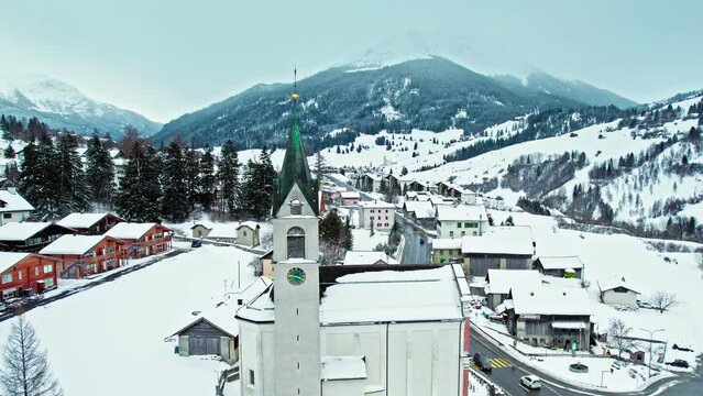 Aerial panoramic view of colourful houses and churches in Surses, Switzerland. Drone view of Houses covered with snow in the middle of the Swiss Alps during winter.