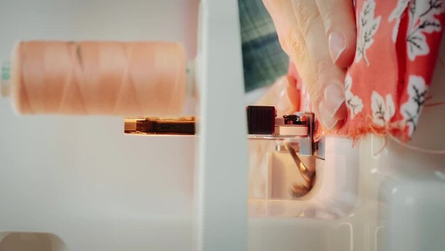 Hands sew fabric on sewing machine. Details of overlock machine. Vertical video