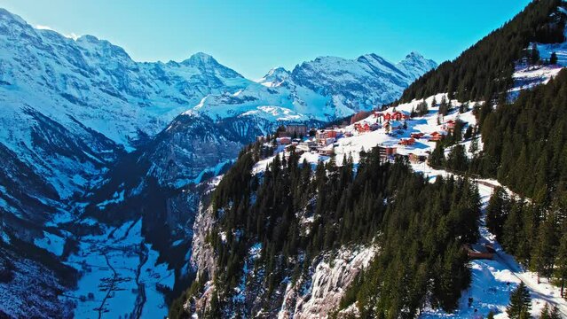 Aerial view of a Swiss mountain village with colourful houses on the cliff in Muren. Panoramic view of Alpine pasture forming a balcony overlooking the steep cleft of the Lauterbrunnen Valley.