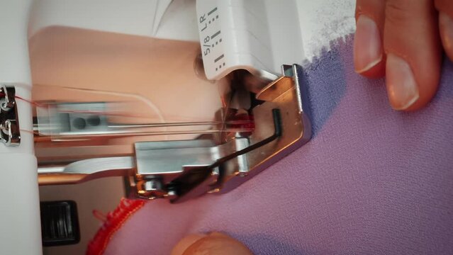Woman sews on sewing machine. Details of overlock with needle. Vertical video