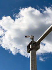 Road surveillance camera on a pole against a cloudy sky