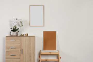 Chest of drawers, table, orchid and picture frames indoors, space for text. Interior design