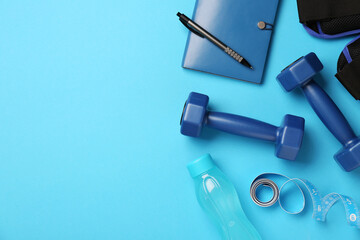 Flat lay composition with dumbbells on light blue background, space for text