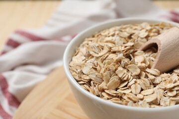Bowl and scoop with oatmeal on table, closeup. Space for text