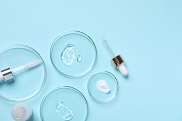Petri dishes with samples of cosmetic serums, bottle and pipettes on light blue background, flat...
