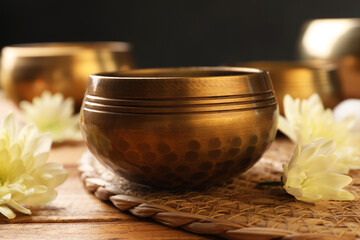 Tibetan singing bowls and beautiful chrysanthemum flowers on wooden table, closeup