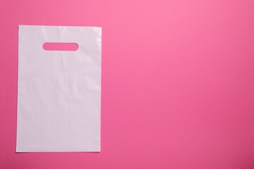 White plastic bag on bright pink background, top view. Space for text