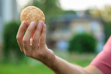 Guy's hand holds mini bread, snack and fast food concept. Selective focus on hands with blurred background