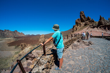 A teenager looks at the lava fields of Las Canadas caldera of Teide volcano and rock formations -...