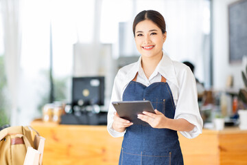 Opening a small business, AHappy Asian woman in an apron standing near a bar counter coffee shop, Small business owner, restaurant, barista, cafe, Online, SME, entrepreneur, and seller concept
