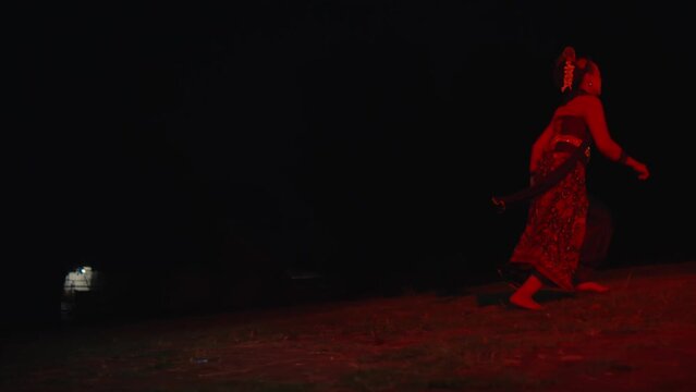 a dancer runs across an empty field crying and sad with a red glow