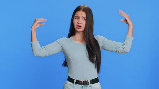 Disappointed Caucasian young woman showing blah blah nonsense gesture with hands, not interested in conversation, gossips, empty promises, rumors, liars. Teenager girl isolated on blue background
