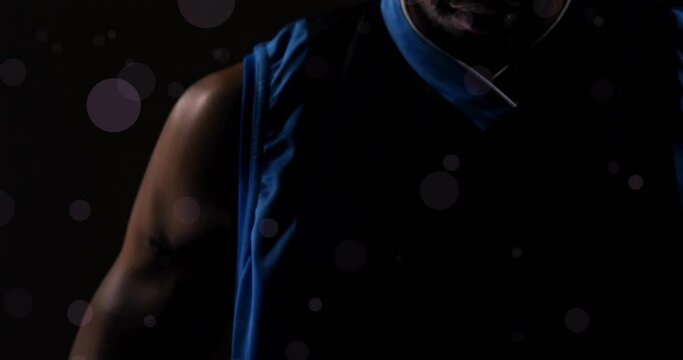 Animation of african ameerican basketball player with ball and spots of light on black background
