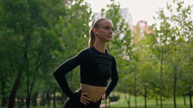 portrait of A girl athlete in a sports uniform performs neck and shoulder bends during a warm-up before training in park