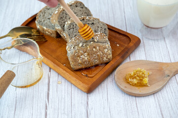 Breakfast set A man's hand is pouring honey onto bread with milk.