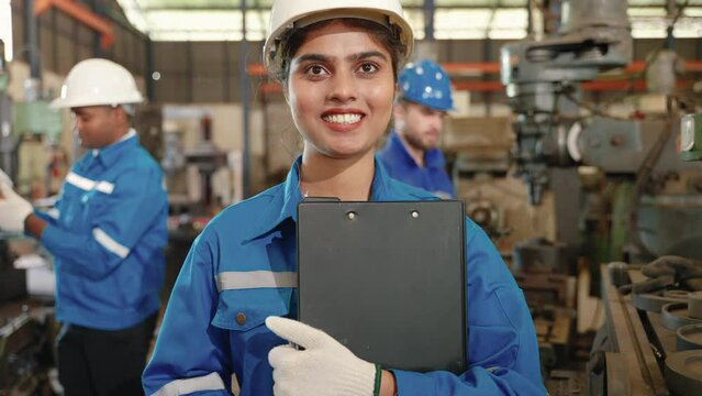 female Indian engineer is standing confidently in a workshop.
