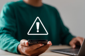 Developer using smartphone with warning triangle sign for error notification and maintenance...