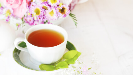 Fototapeta na wymiar herbal tea in a cup, fresh flowers in the background, morning tea or herbal medicine concept