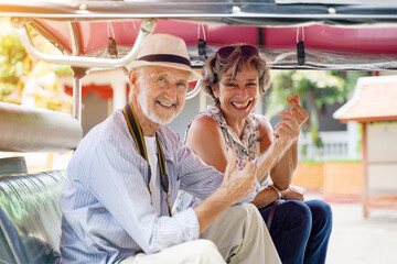 Closeup American senior tourist man with his friend European poses happy thumbs up and mini heart...