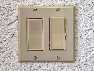 Dual wall rocker light switches with a dimmer slider on a white wall