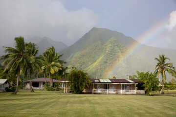 A colorful rainbow over the beach mountains at sunset in Tahiti 