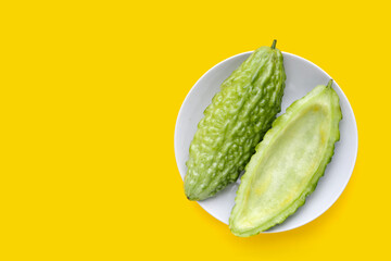 Bitter melon in in white plate on yellow background.