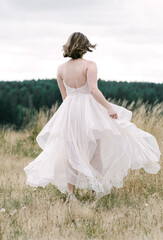 Bride running in dress through a field