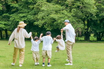 夏休みに公園を手を繋いで歩く家族・ファミリー（レジャー・アウトドア・ピクニック・キャンプ・思い出）
