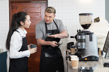 Barista cafe wearing apron and prepare coffee grinder pour at coffee shop. Worker making coffee on steam espresso coffee machine. Small business concept