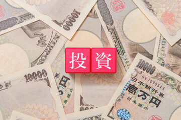 赤色のブロックに書かれた投資の文字　一万円札 - obrazy, fototapety, plakaty