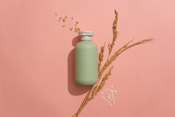 An unlabeled cosmetic bottle and rice are displayed on a pink background. Blank space for design....