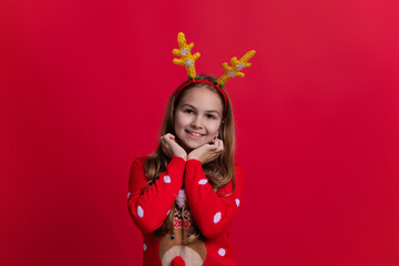Happy 2024 New Year. Christmas shopping sale. Teen girl wearing Xmas sweater and antlers isolated on red. Merry Christmas. New Year holiday in winter. Teen girl having fun. Wintery sweater