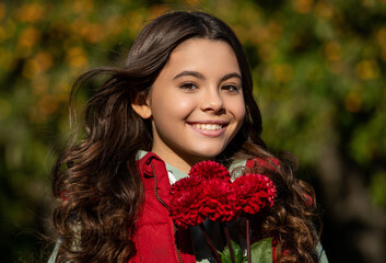 Naklejka premium teenager girl with red autumn flowers outdoor. teenager girl with autumn flowers bouquet.