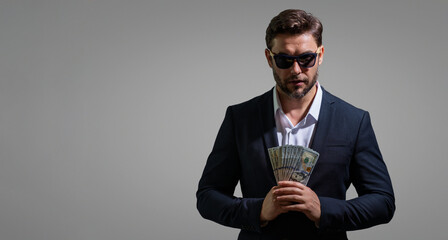 Man holding cash money in dollar banknotes on isolated gray background. Studio portrait of...