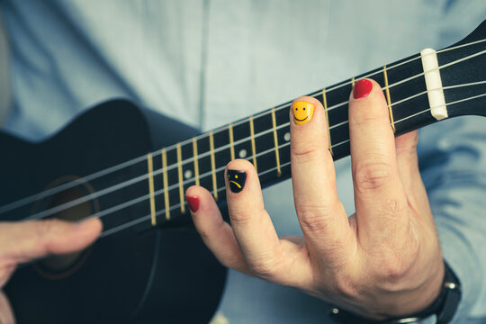 Man with painted nails. A musician with painted fingernails plays a ukulele in close-up. A musical concept. Design of male nails. men manicure.