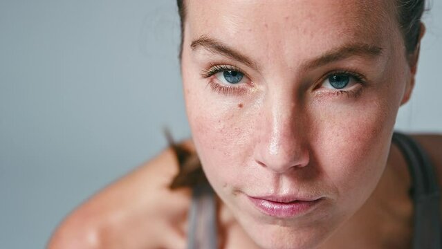Studio close up shot of woman wearing fitness clothing starting sprint race against grey background - shot in slow motion