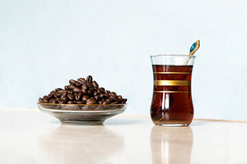 glass mug in the traditional Turkish style with black coffee stands with coffee beans lying on the...