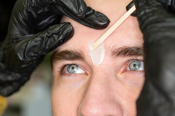 Removal of fused eyebrows in a man with a hot shower. cosmetologist does the procedure of eyebrow...